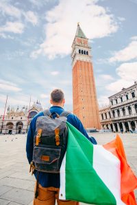 man with italian flag at saint marco square summer vacation